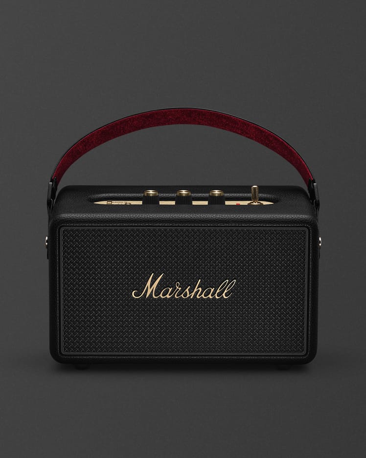 Marshall Kilburn III Black and Brass portable Bluetooth speaker, featuring a gold logo and brown carrying handle, is shown from the front against a plain background.