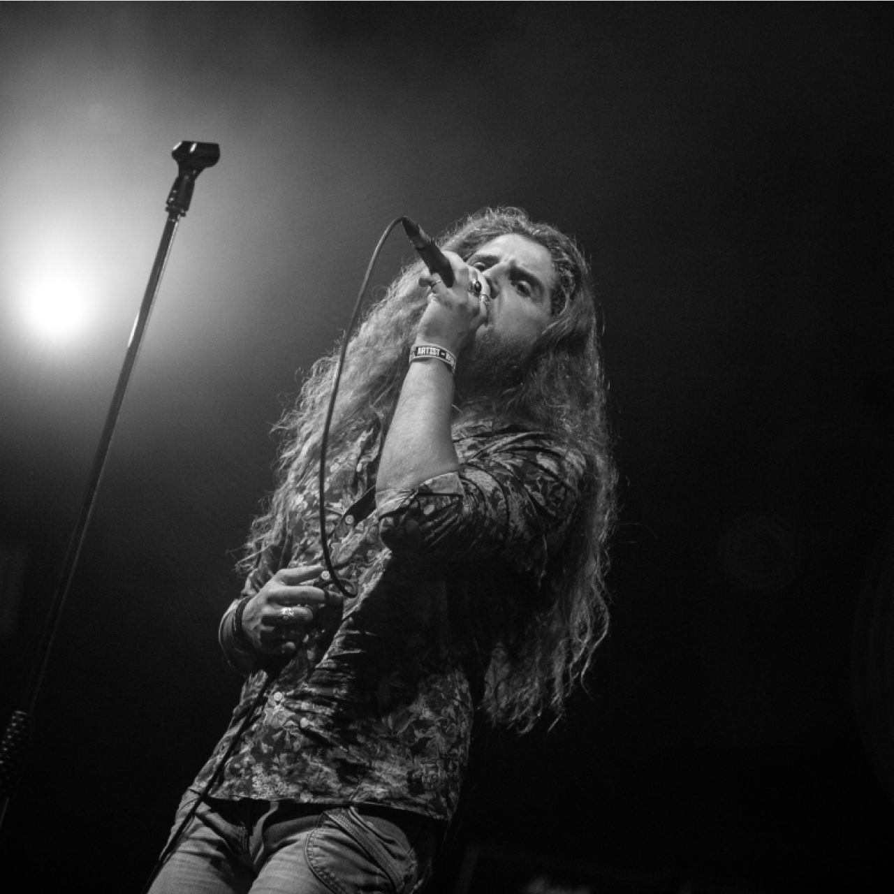 A man with long hair singing into a microphone.
