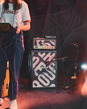 Musician playing an electric instrument in front of the personalised Rough Trade Marshall Amp.