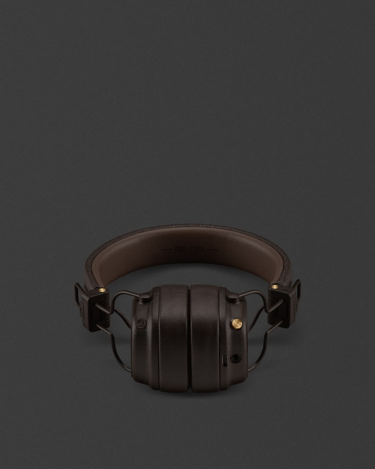 Un par de auriculares de botón Marshall Major V Brown sobre un fondo oscuro.