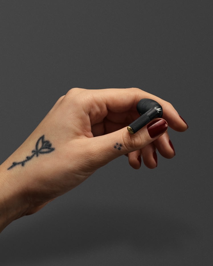 Marshall Minor IV Blackトゥルーワイヤレスイヤホンを手にする女性。