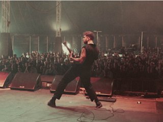 A man playing guitar on stage in front of a crowd.