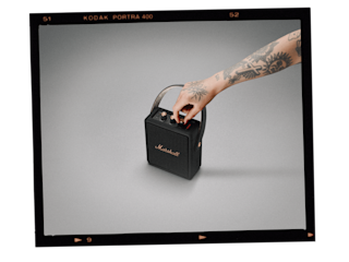 A tattooed man turns on Marshall's black Stockwell II speaker.