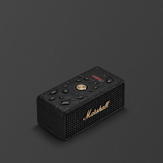 A black and brass Marshall Emberton III portable speaker with water droplets on its surface, shown on a dark background.