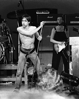 Iggy pop is on stage with David Bowie playing piano.