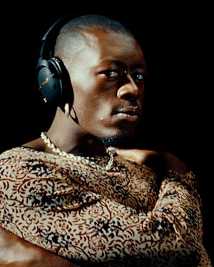 Un hombre con auriculares over-ear bluetooth Marshall Monitor III A.N.C. Black y un conjunto estampado.