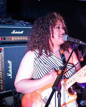 Una cantante y guitarrista actuando en un pequeño local