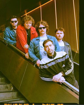 Cinco hombres de la banda Gallus posando para una foto de grupo.