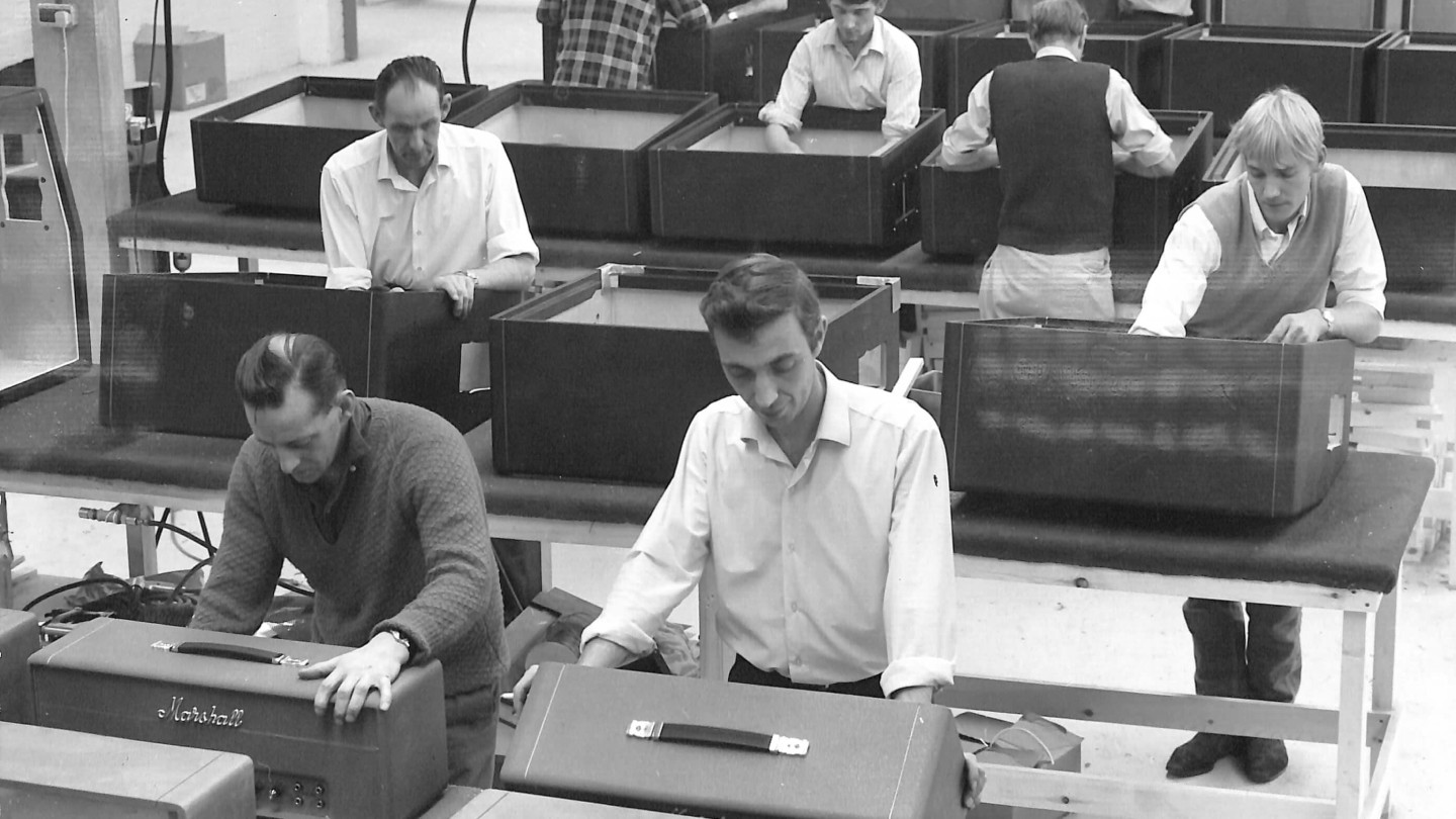 Black and white picture of people working side by side building Marshall amps. 