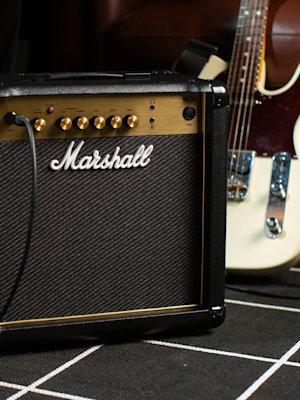 The Marshall MG15G Combo in front of the electric guitar in rehearsal room.
