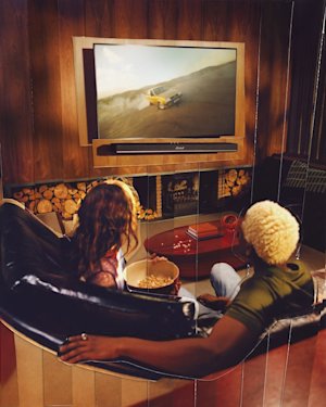 Two friends watching to the TV connected to the Marshall Heston 120 TV Sound bar