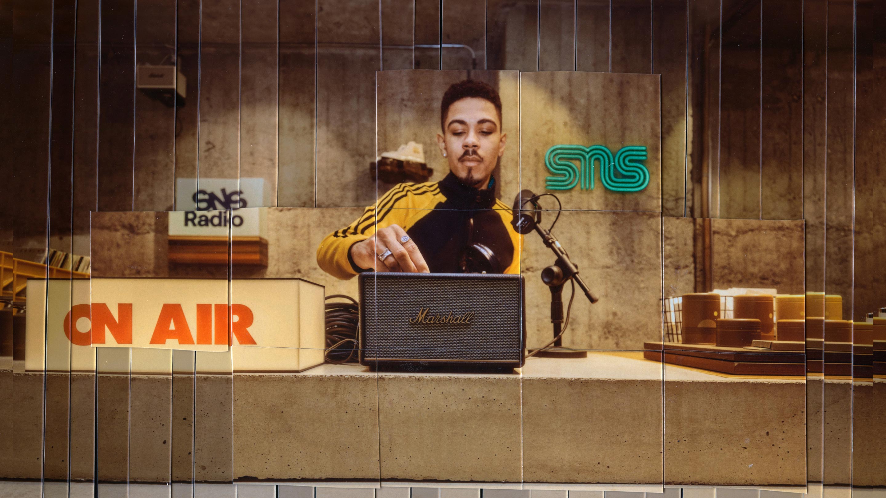 A young man adjusts controls on a marshall speaker at a radio station setup with neon signs and vintage decor.