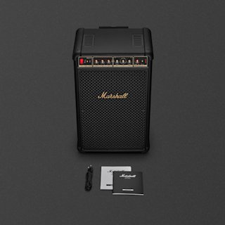 A black Marshall Bromley 750 party speaker with a USB-C power cable, a user manual, and a legal & safety booklet displayed on a dark surface.