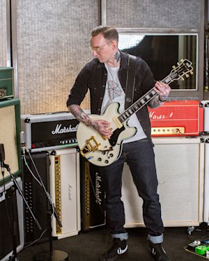 Different Marshall amps in a recording studio used by a musician in a grey t-shirt