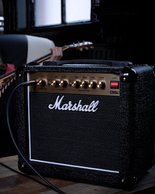 Right side view of the Marshall DSL1 Combo with guitar player blurred in the background.