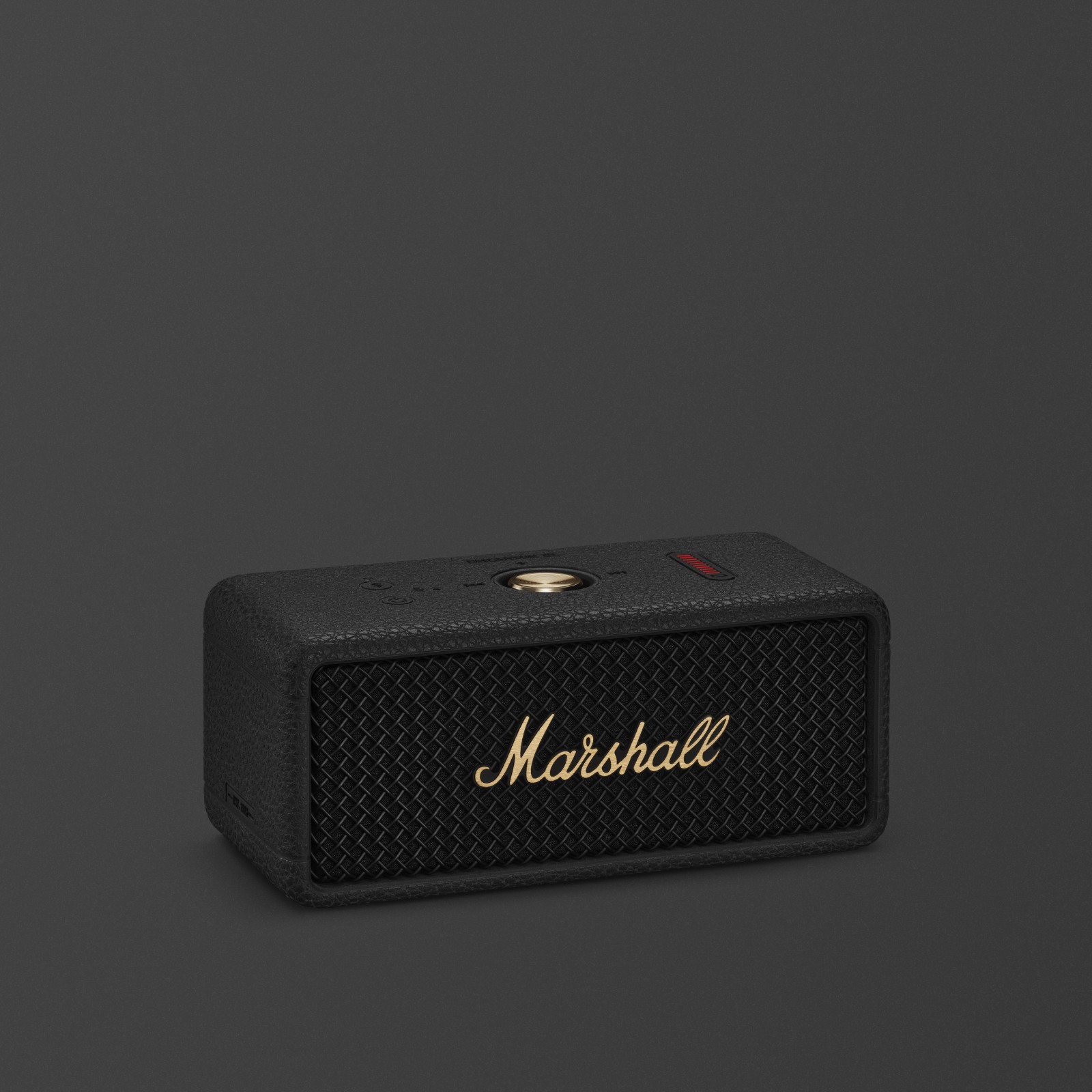 Marshall Emberton III Schwarzer und messingfarbener tragbarer Bluetooth-Lautsprecher vor dunkelgrauem Hintergrund.