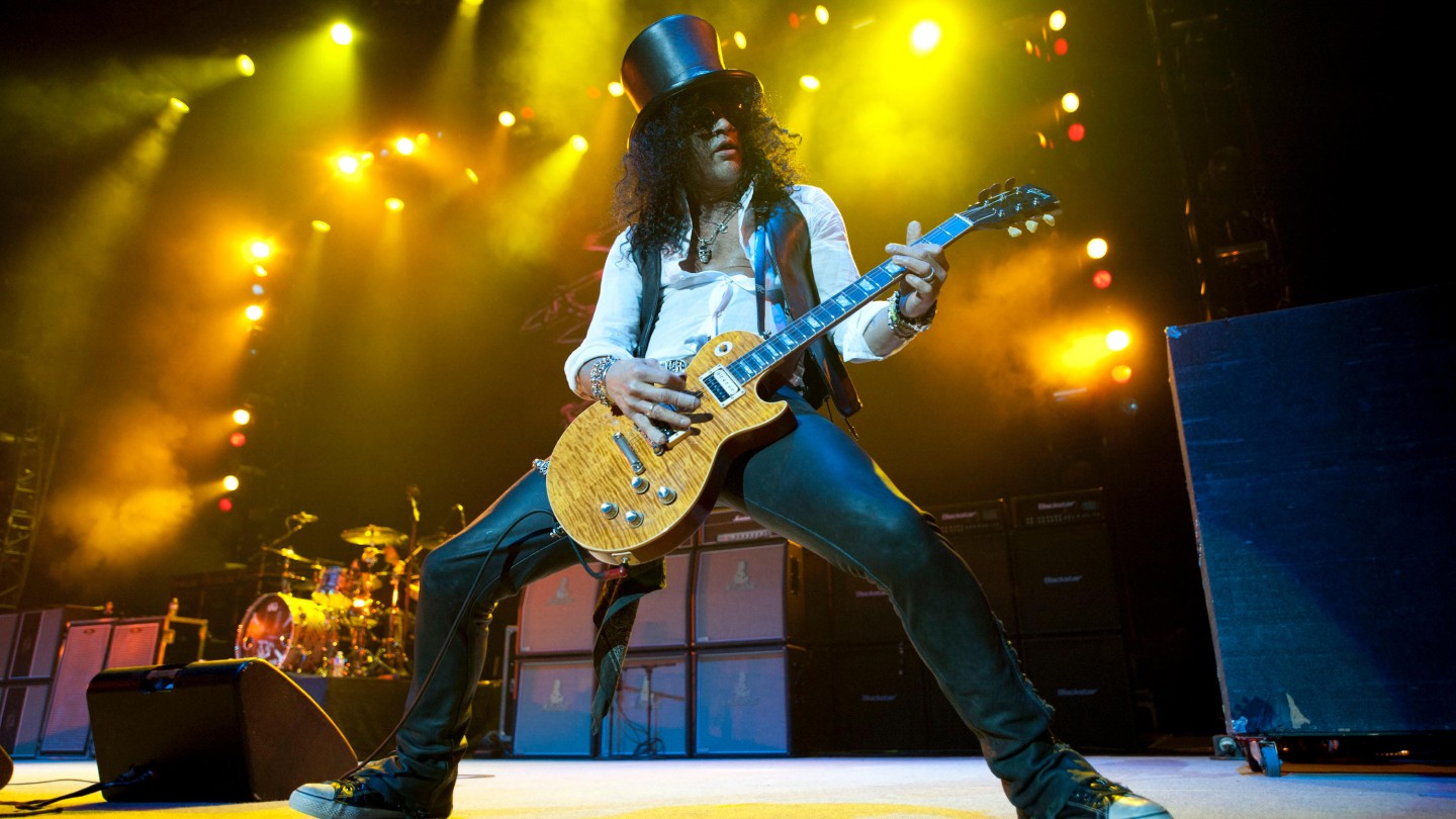Slash performing on stage in front of his signature Marshall amps.