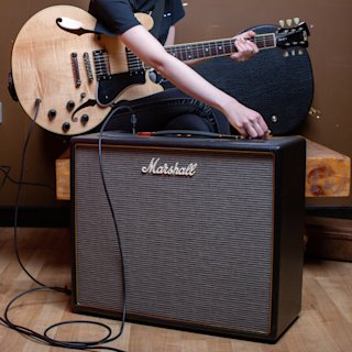 Guitarrista con guitarra beige sentado y afinando el Marshall Origin50 Combo.