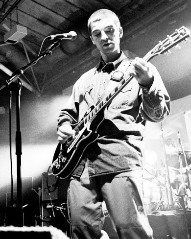 Image en noir et blanc d'Oasis se produisant sur scène en 1994.