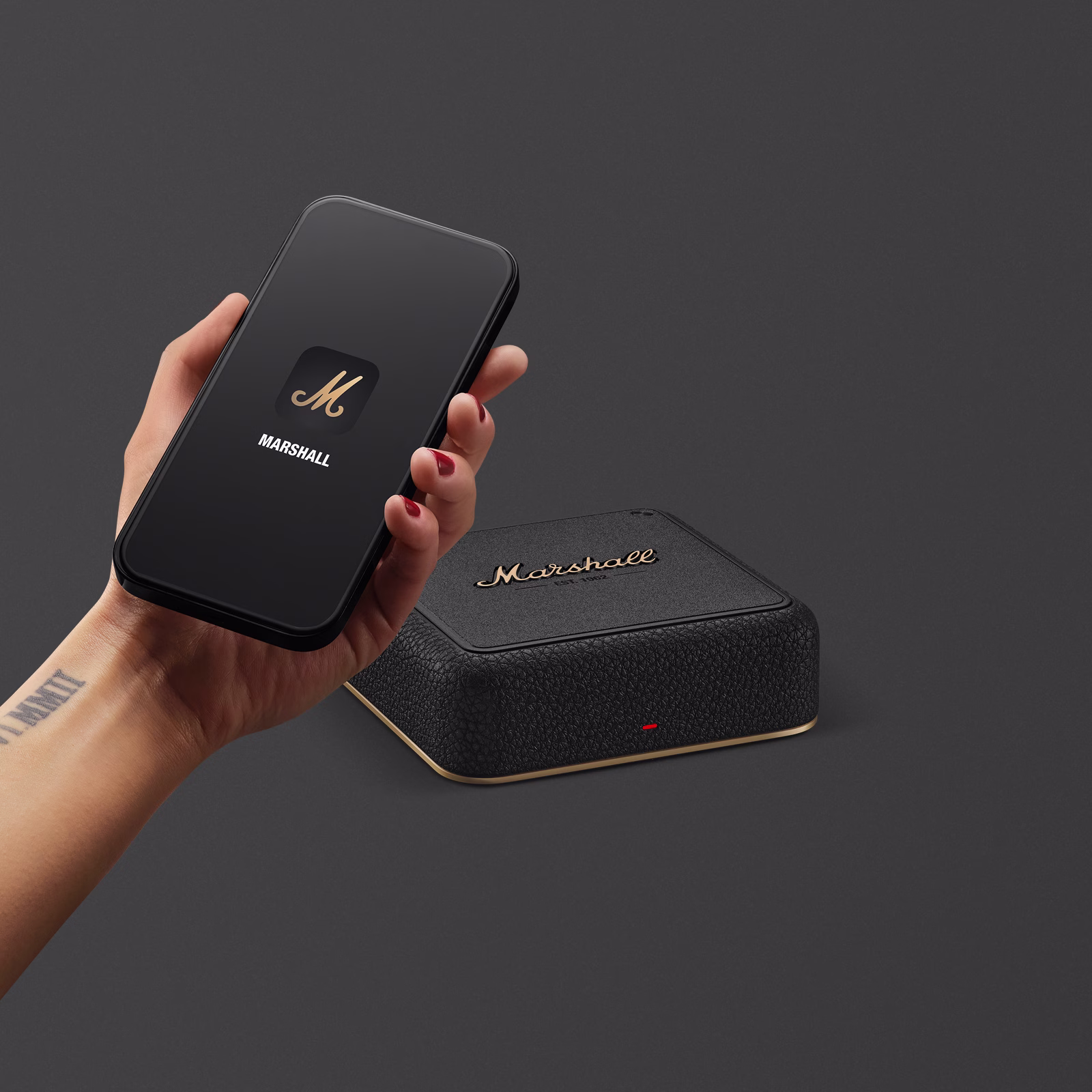 A hand holding a smartphone, positioned above a Marshall Heddon.