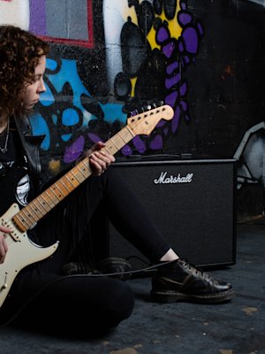 Guitarist playing in front of the Marshall CODE50 Combo with graffiti wall in the background.