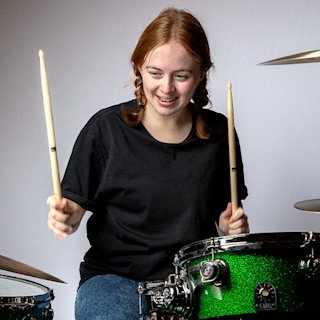 Mini Fairhurst playing on a green Natal drum