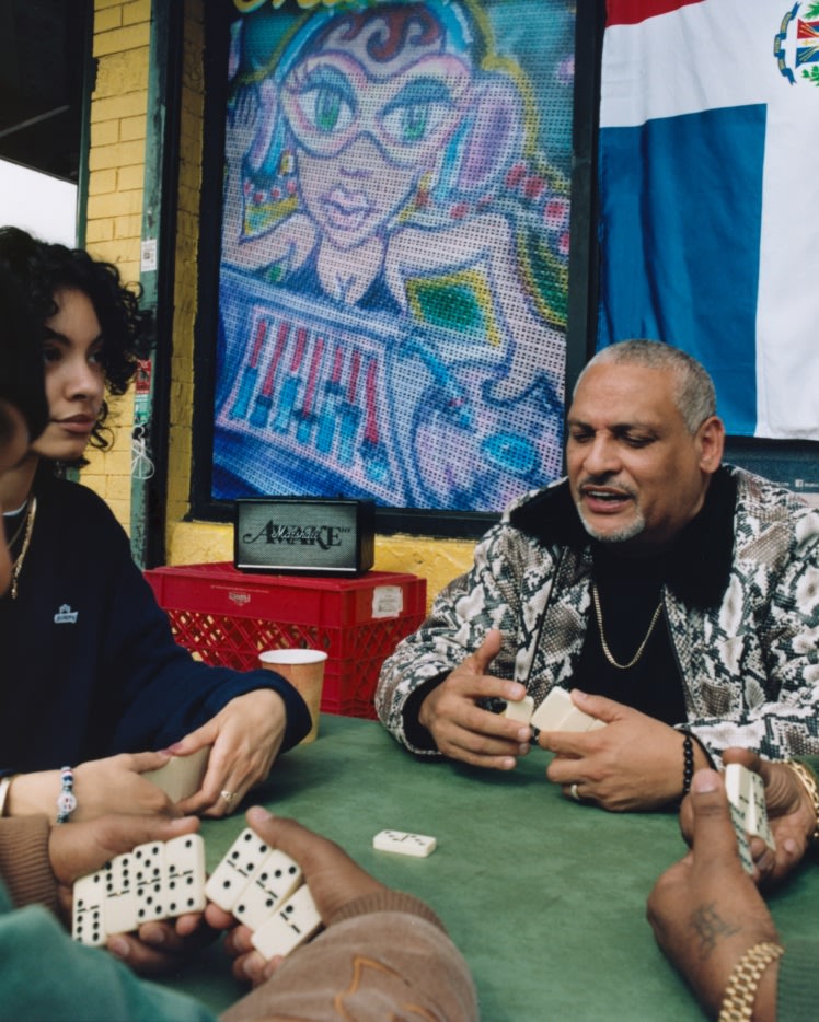 People playing dominoes at a table with Marshall Acton III Awake NY Edition speaker in the background.