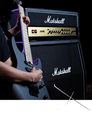 A person playing a guitar beside Marshalls JVM210 Head