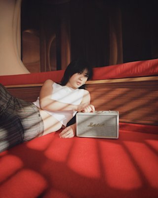 Girl increasing the volume of Marshall Cream Speaker