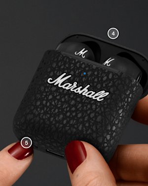 Mano sujetando un estuche de carga Minor III abierto, mientras se pulsa el botón Bluetooth.