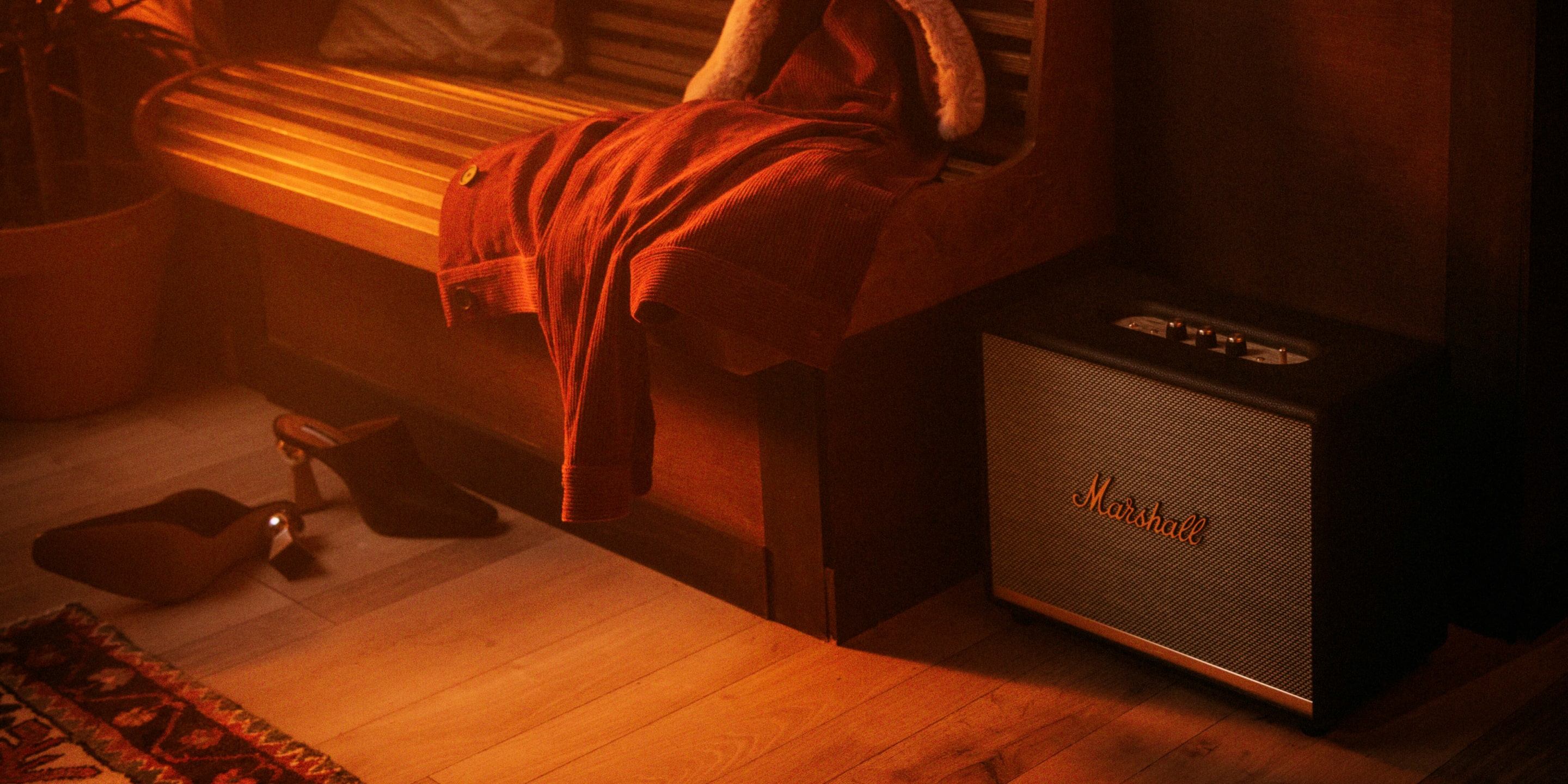 A Refurbished Marshall Speaker placed on the floor, beside the couch of a living room.
