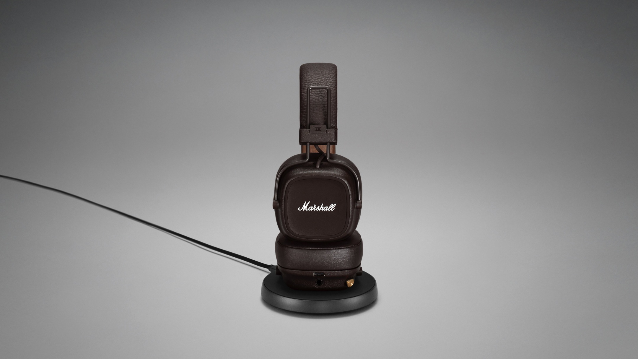 Marshall MAJOR IV headphones displayed on a sleek black stand.