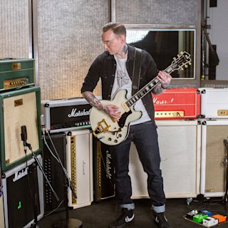 Mann spielt Gitarre in einem Musikstudio, umgeben von Marshall-Verstärkern