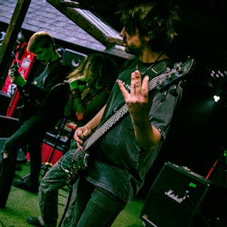 A musician playing in a small venue with a green light on top of him