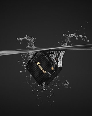 Marshall Willen II Black and Brass portable speaker partially submerged in water with splashes around it, highlighting its waterproof design.