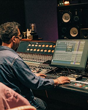 Person sitting by a mixing desk in a studio