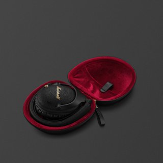 A pair of black Monitor III A.N.C. over-ear headphones are placed inside a round, open black case lined with red velvet fabric against a dark background.