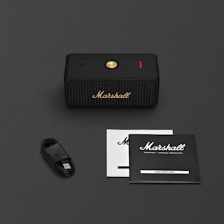 A black Marshall Emberton II portable speaker together with a USB charging cable and two instruction booklets, all placed on a dark surface.