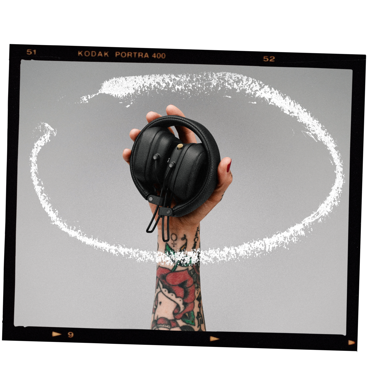 A tattooed hand holding a pair of Marshall Major IV headphones.