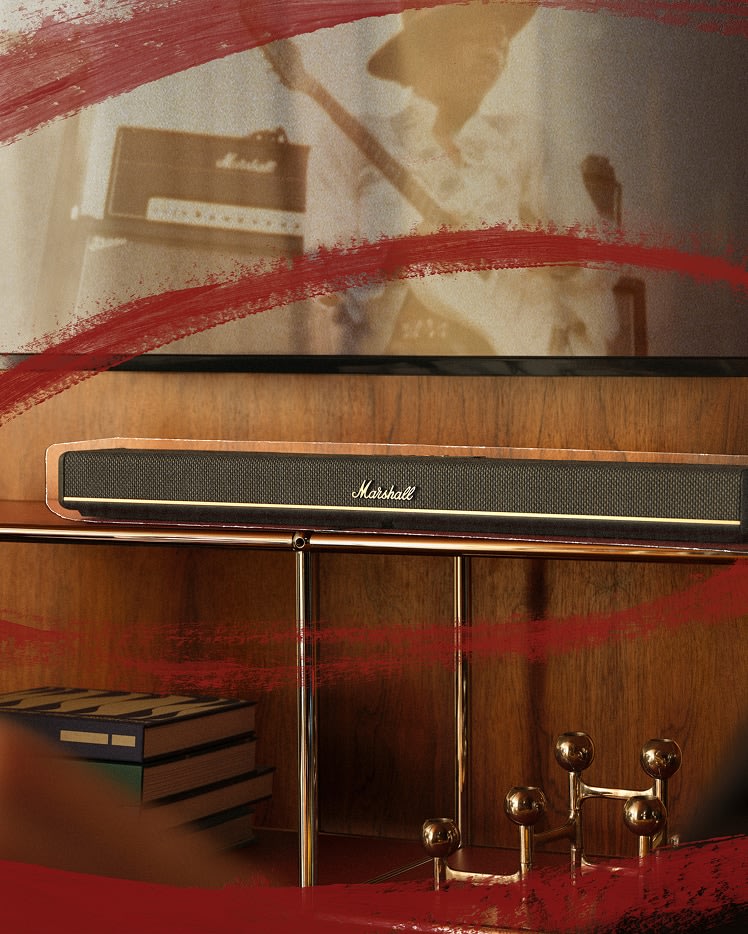 Marshall Heston 60 Black soundbar sit on a wooden shelf below a TV showing a vintage music scene, with books and a metallic decorative object nearby.