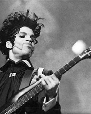 Black and white image of prince playing guitar on stage