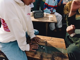 People sit at a wooden table, playing with small white blocks with Marshall Acton III Awake NY Edition and paper cups in the background.