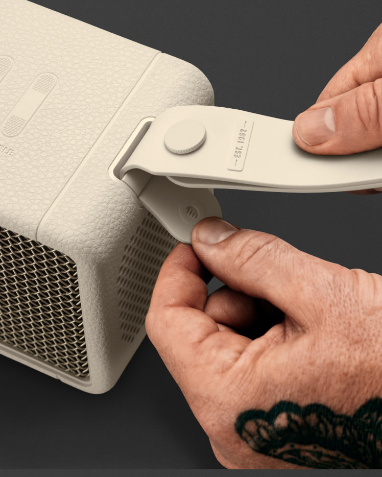 A person is using a tool to open up a Marshall Middleton Cream speaker.