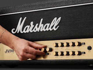 A person is holding a Marshall JVM205 Head amplifier.