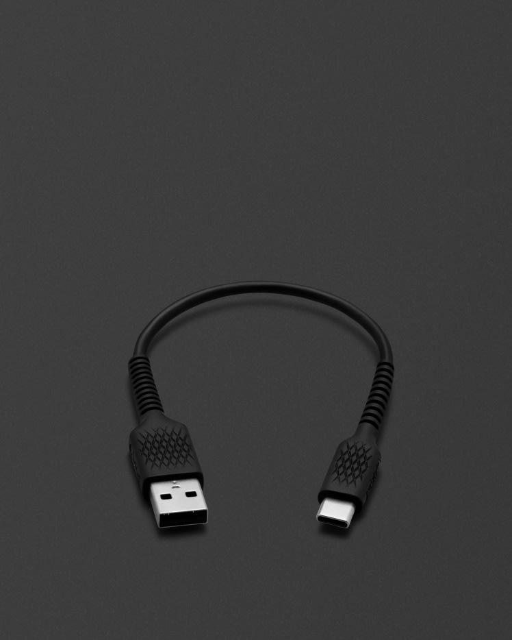 Un CABLE DE CARGA CORTO USB-C Marshall negro conectado a una superficie negra.