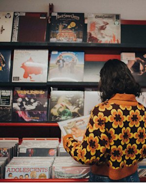 A girl looking at vinyls at a record store.