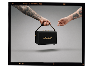 A hand holding a portable Marshall KILBURN II speaker.