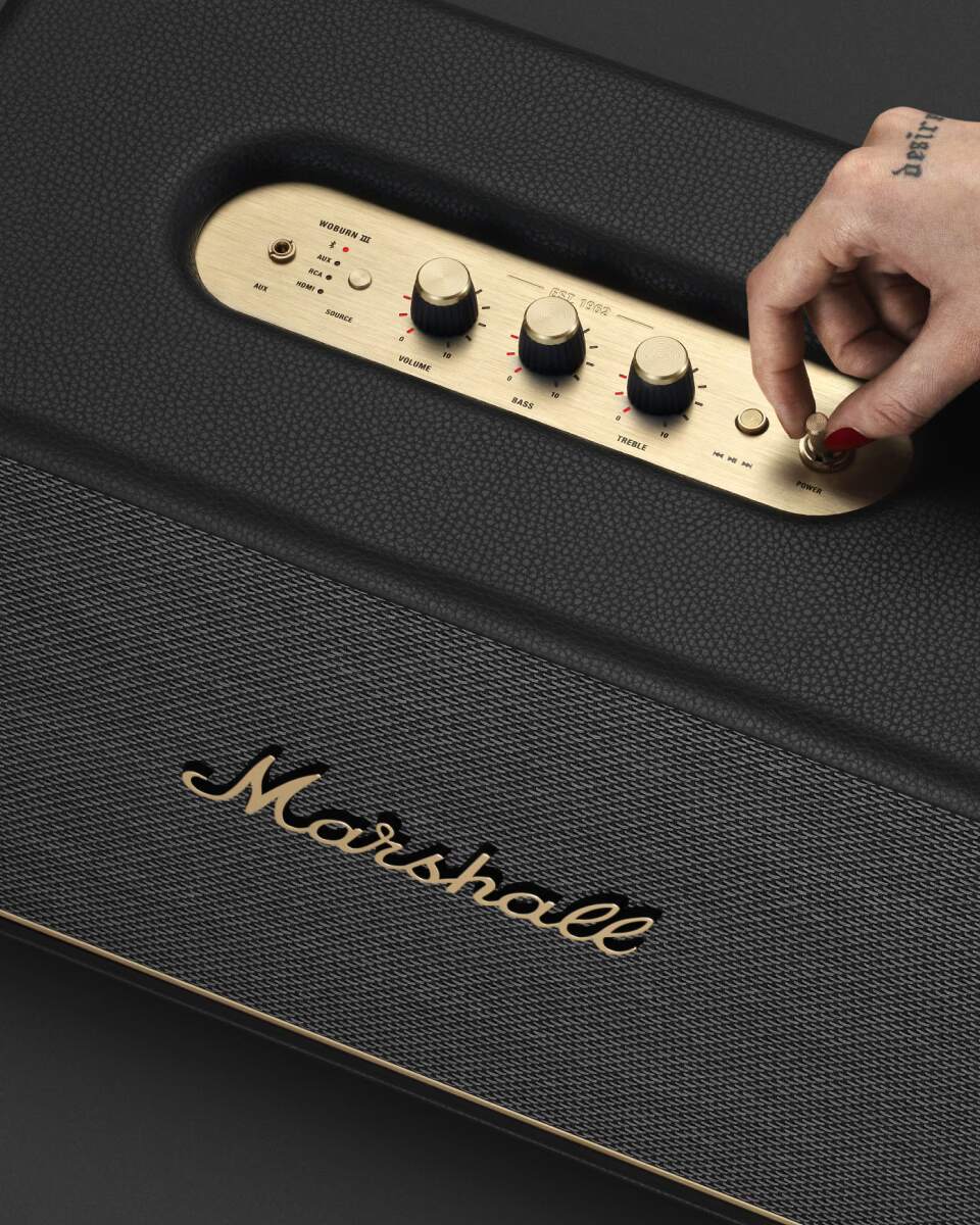 Marshall speaker is shown with a person's hand turning it on.