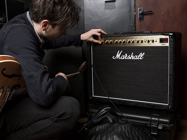 Una persona de pelo corto ajustando el sonido del Combo DSL40