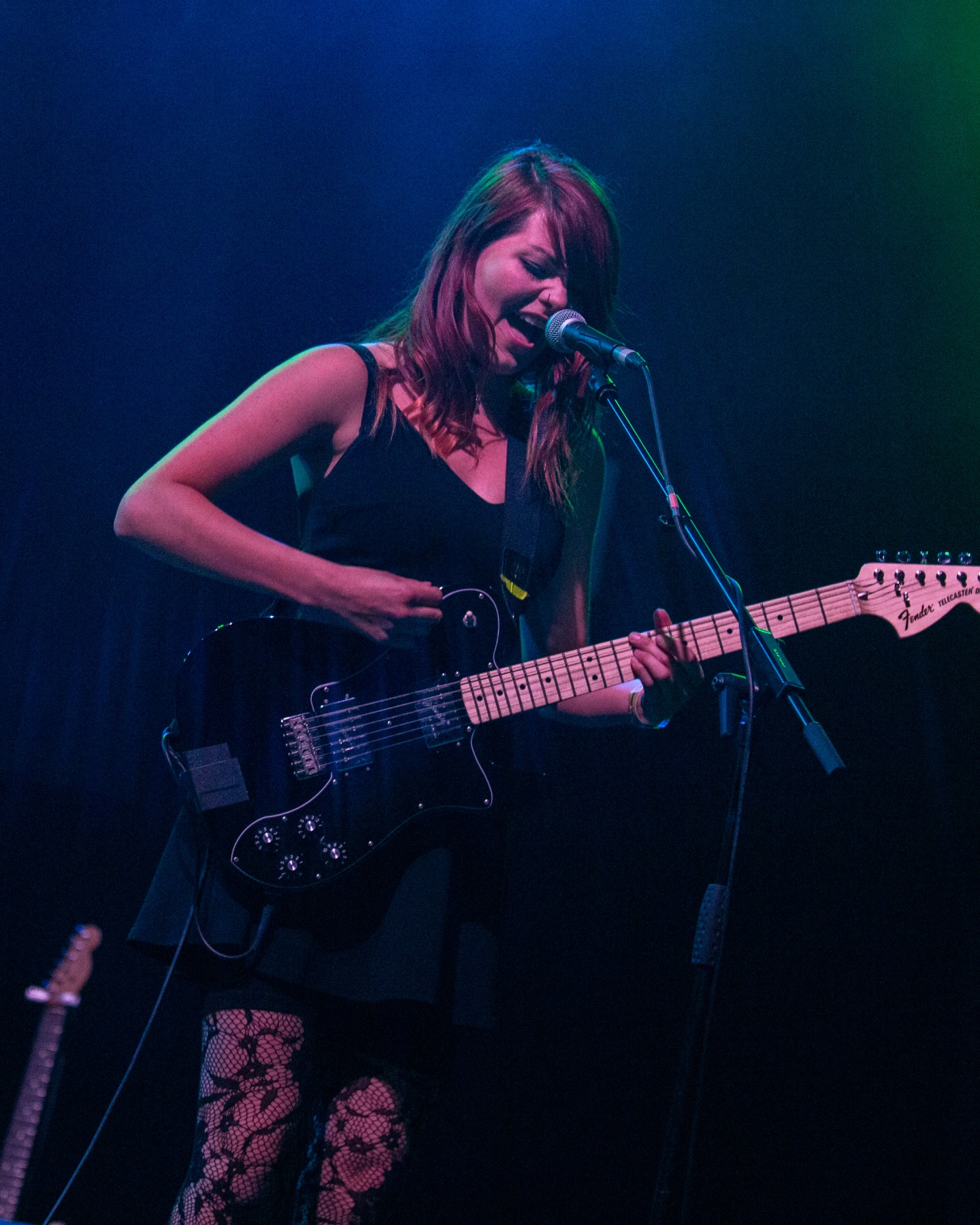 Una imagen que muestra a Rews actuando en un escenario con una guitarra